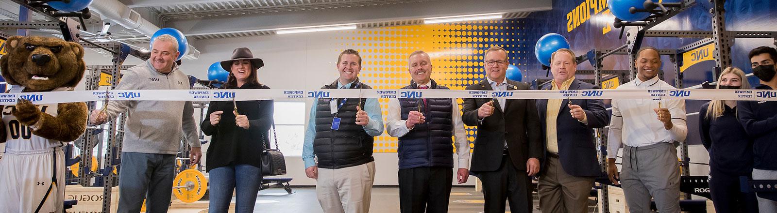 Donors participating in a ceremonial ribbon cutting for the athletics empower center