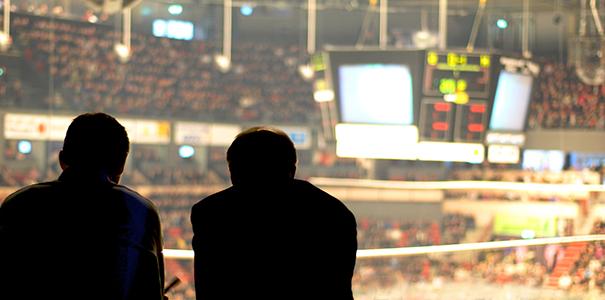 two people in silhouette watching a sporting event at a large arena